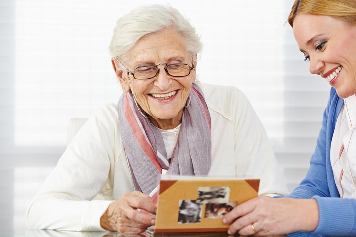 elderly woman and caregiver looking at photo album